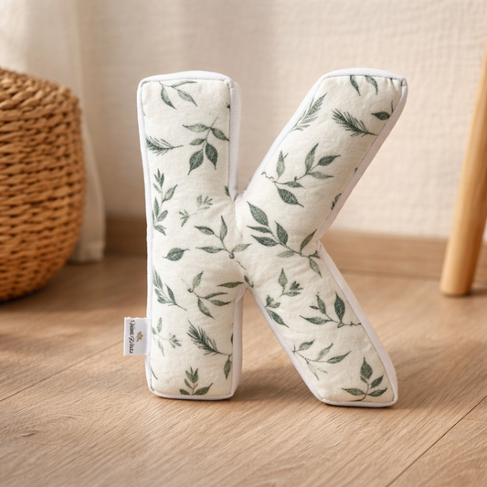 Personalized botanical letter K pillow in neutral nursery setting