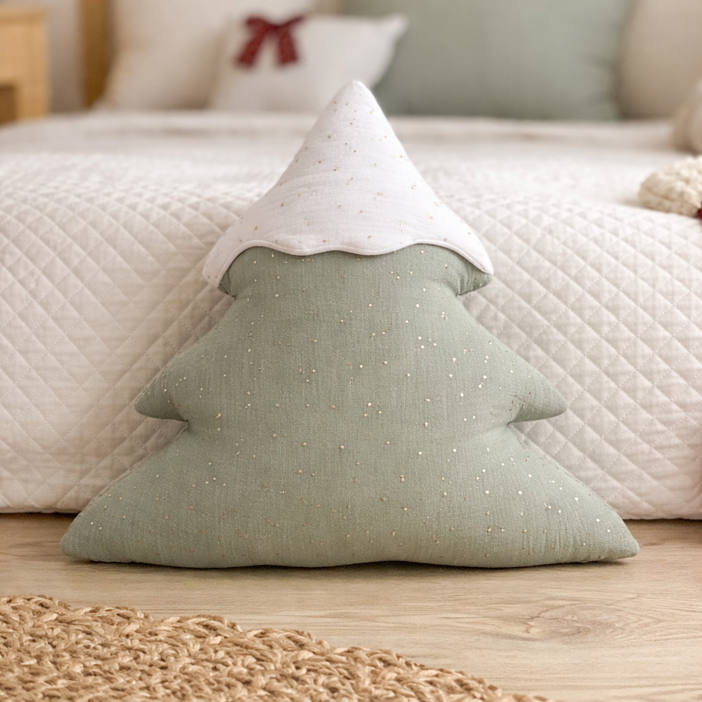 Green tree-shaped pillow on a wooden floor with a neutral-colored sofa in the background