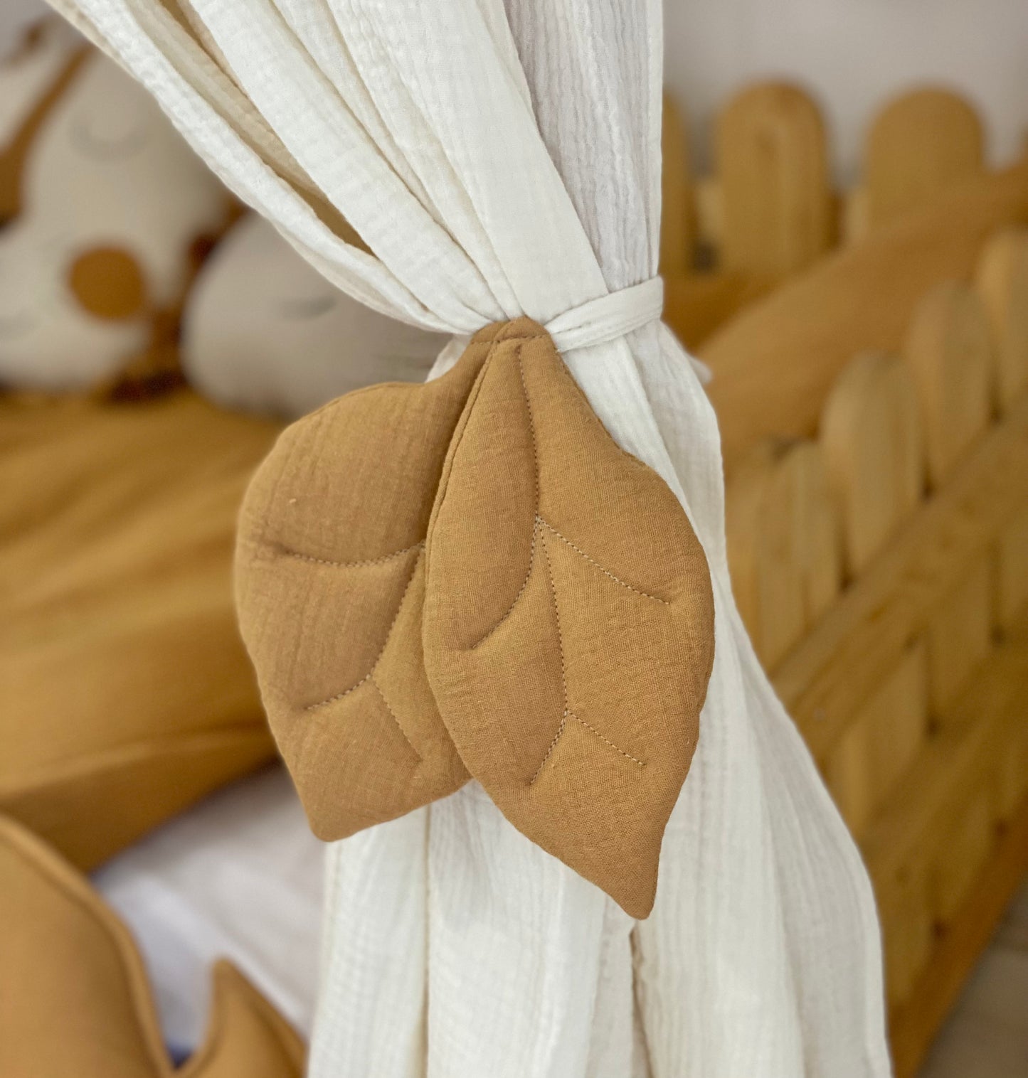 Cream canopy with leaf tiebacks over Montessori bed